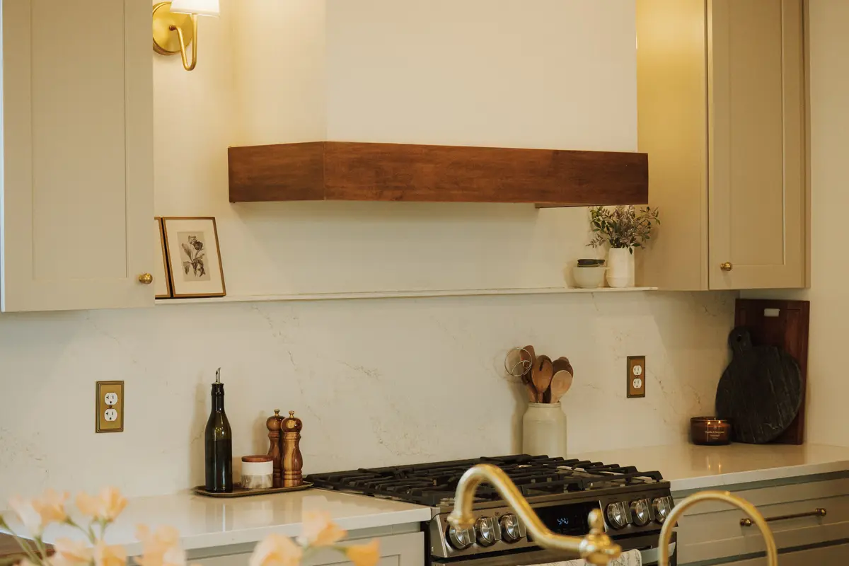 Farmhouse kitchen with a walnut range hood, brass sconce, and marble backsplash