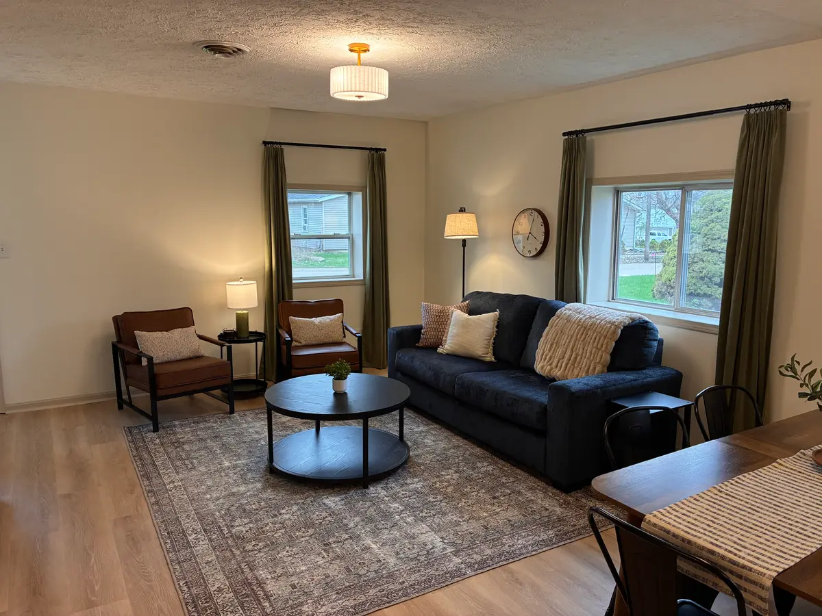 Living room with a navy sofa, round coffee table, and green curtains