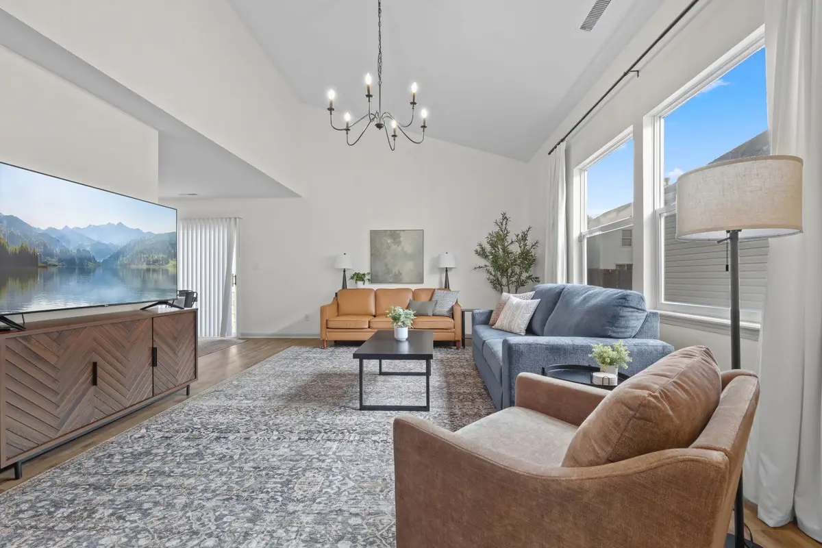 Living room with a cognac leather chair, layered rug, and tall windows