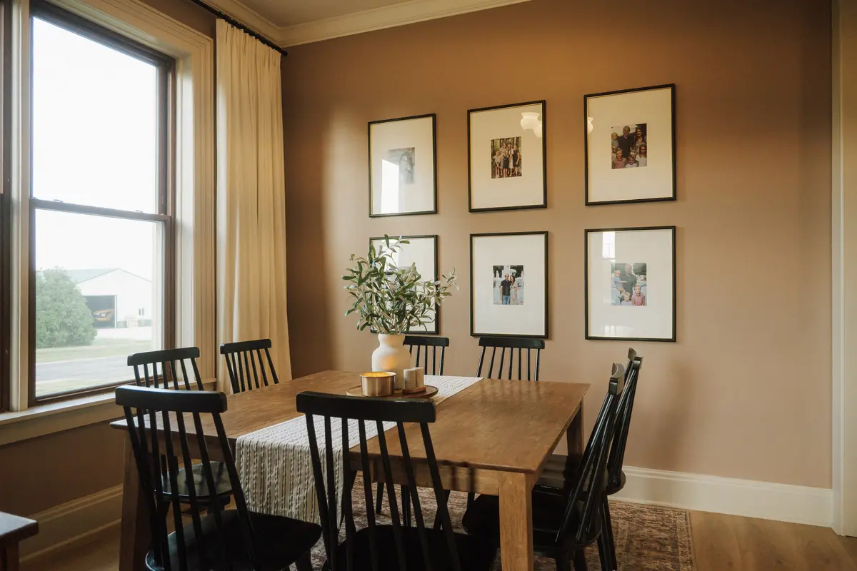 Dining room with framed black-and-white prints, spindle chairs, and an olive branch centerpiece
